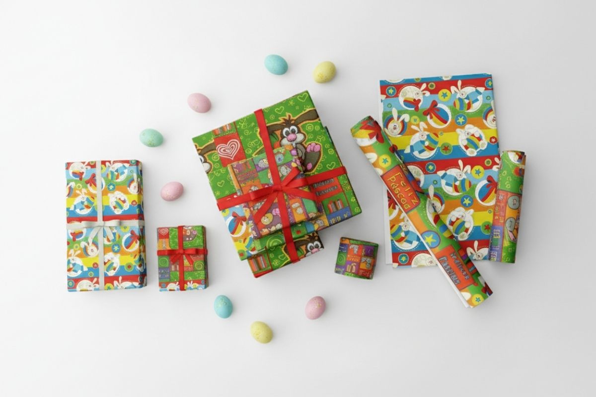 Visão aérea de presentes embalados com papéis de coelhos em fundo verde e azul, demonstrando a variedade da coleção.